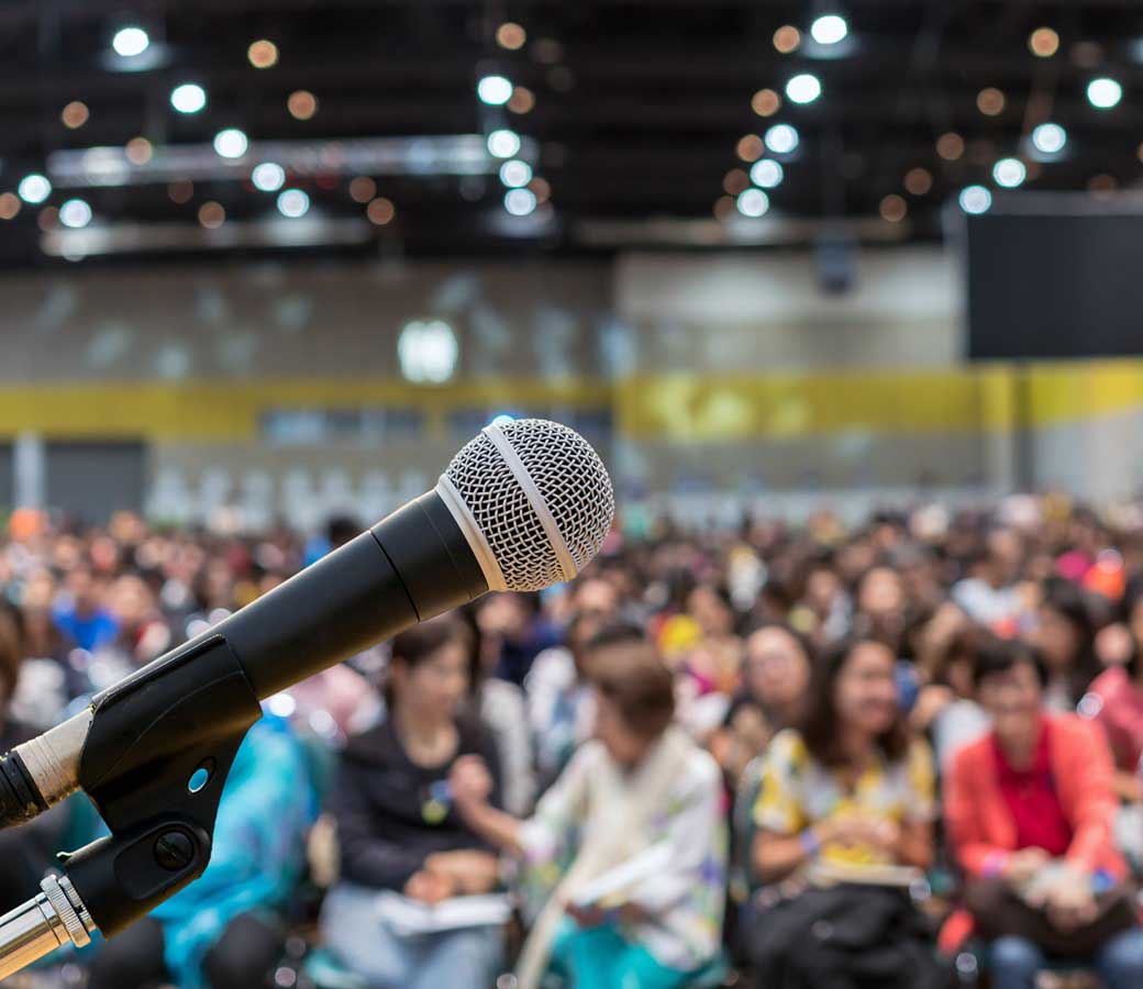 Microphone over the Abstract blurred photo of conference hall or
